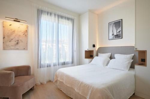 une chambre avec un lit, une chaise et une fenêtre dans l'établissement Cannes Croisette Port Canto Les Dunes, à Cannes