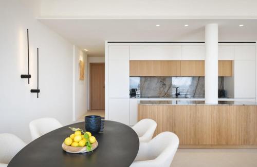 une cuisine avec une table noire et des chaises blanches dans l'établissement Cannes Croisette Port Canto Les Dunes, à Cannes