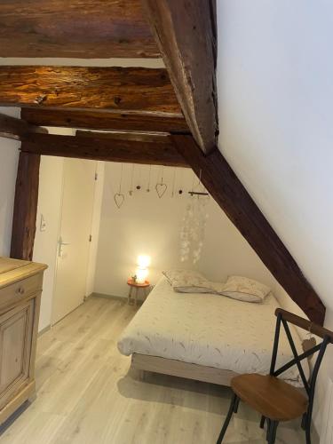 une chambre avec un lit et une chaise dans un grenier dans l'établissement Le cœur d'Alsace 2 à 6 pers à 5 min de Ribeauvillé, à Guémar