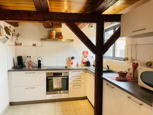 une cuisine avec des appareils blancs et un plafond en bois dans l'établissement Le cœur d'Alsace 2 à 6 pers à 5 min de Ribeauvillé, à Guémar