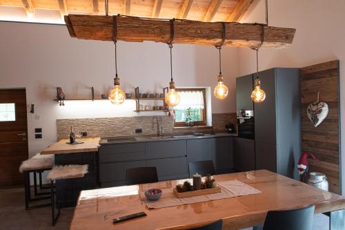 卡斯泰洛泰西諾的住宿－Chalet Grifone - Chalet Maso Vecchio nel cuore del Lagorai Trentino，厨房配有吊灯和木桌