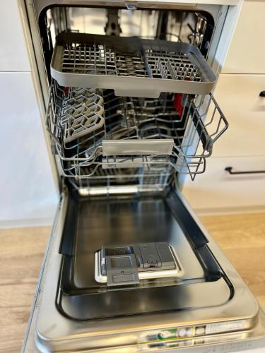 a dishwasher with its door open with a dish rack at Resita Dream Apartament in Reşiţa