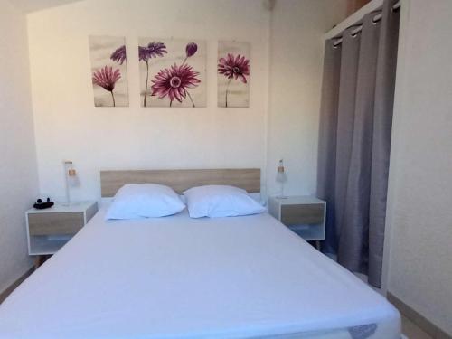 - une chambre avec un lit blanc et deux photos sur le mur dans l'établissement Appartement T2 Mezzanine, 6 couchages, bord de plage, parking privé, proche commerces et Aqualand - FR-1-81-47, à Port-Leucate