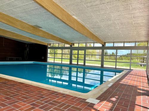 une grande piscine avec un grand groupe de fenêtres dans l'établissement Le Petit Lynx - Chalet cocooning Haut Jura, à Saint-Laurent-en-Grandvaux