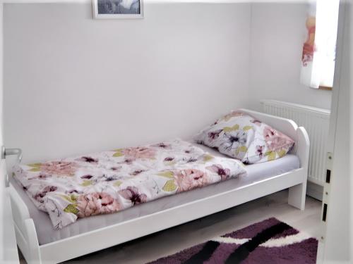 a white bed in a room with pink flowers at 3 bedrooms apartement with furnished garden and wifi at Rakovica in Rakovica