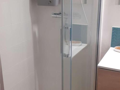 - une porte de douche en verre dans une cuisine blanche dans l'établissement Carnac : Studio Cabine avec Piscine chauffée, proche Plage et Thalasso, Animaux bienvenus - FR-1-477-186, à Carnac