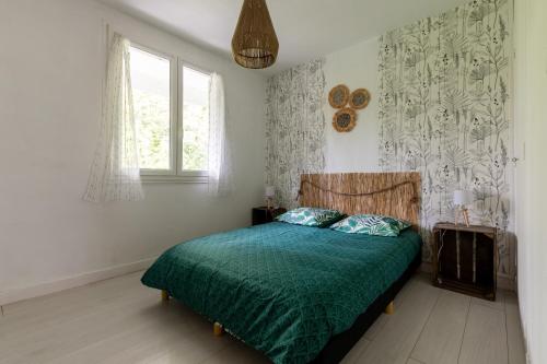 una camera da letto con un letto con un piumone verde e una finestra di La Cigale de Provence - Maison avec vue montagne a Le Cheylard