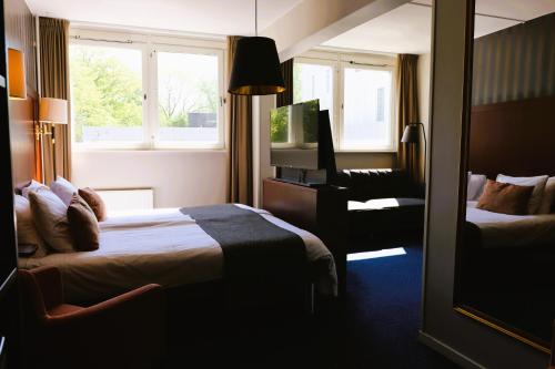 a hotel room with two beds and a chair at Vänerport Stadshotell i Mariestad in Mariestad