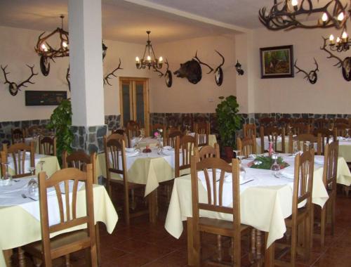 un comedor con mesas blancas, sillas y astas en la pared en Casa Concha, en Almadén de la Plata