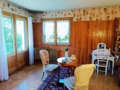 un salon avec une table, des chaises et des fenêtres dans l'établissement La Maison des Praz, à Saint-Gervais-les-Bains
