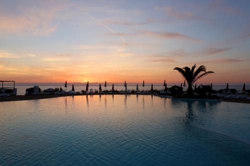 a large swimming pool with a sunset in the background at Acqua di Mare Hotel e Resort in Sorso