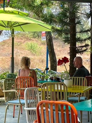 two people sitting at a table under a green umbrella at Pearl Beach Homestay - Cua Dai Beach, Hoi An in Hoi An
