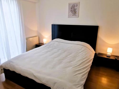 une chambre avec un grand lit blanc avec deux lampes dans l'établissement CAP AUX SABLES avec garage, à Les Sables-dʼOlonne