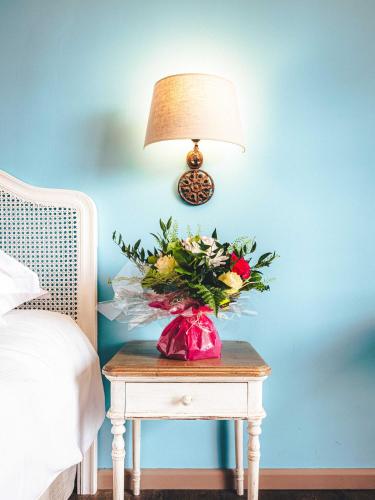 a vase of flowers on a table next to a lamp at Le Suffren Hôtel in Grimaud