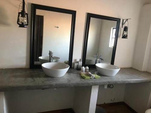 a bathroom with two sinks and two mirrors at Big Cats Namibia Self Catering Farm Guesthouse in Outjo