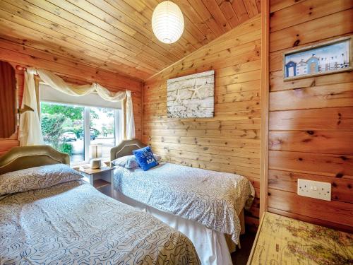 a bedroom with two beds in a log cabin at Ty Glan Mor the Beach House in Llangoed