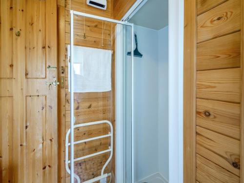 a glass shower in a room with a wooden wall at Ty Glan Mor the Beach House in Llangoed