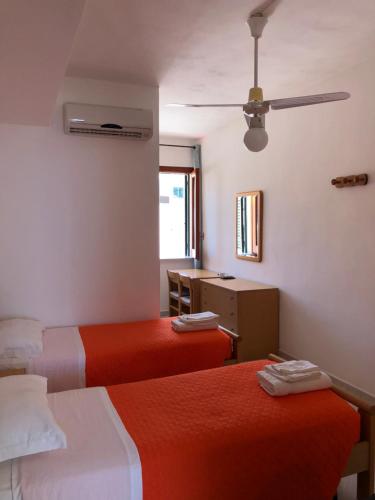 a hotel room with two beds and a desk at Hotel Ariston in Ustica