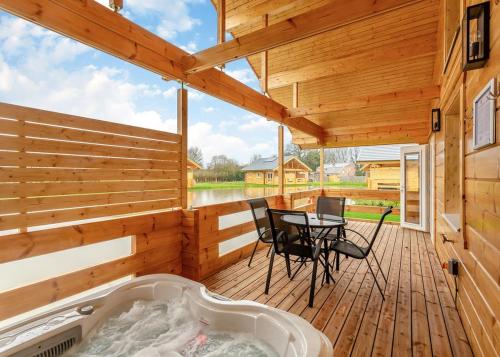 a wooden deck with a tub and a table and chairs at Holly Tree Lodges in York