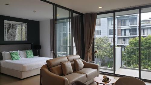 a living room with a couch and a bed and windows at Apartment 55 sqm 1bed 3rd floor with poolview and mountainview in Ban Huai Sok Noi