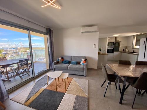 un salon avec un canapé et une table ainsi qu'une salle à manger dans l'établissement Le Danieli sur les quais, au Grau-du-Roi