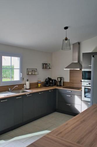 d'une cuisine avec des placards gris, un évier et une fenêtre. dans l'établissement Gîte à la ferme - le Boupère, à Le Boupère