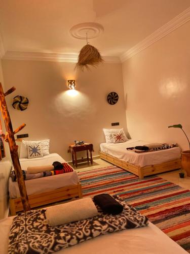 a room with three beds and a rug at CHILL SURFER HOSTEL in Tamraght Ouzdar