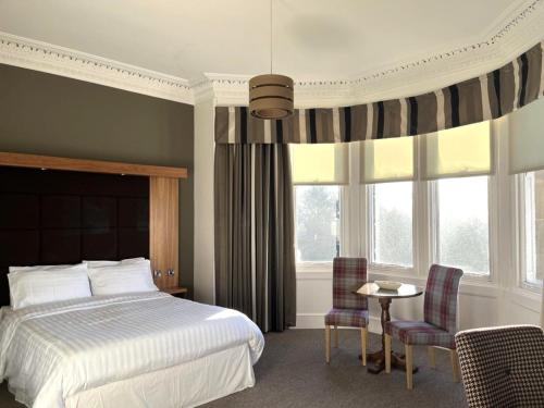 um quarto com uma cama, uma mesa e cadeiras em The Strathearn Hotel em Fife