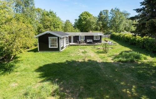 a small black house in a field with a yard at Nice Home In Jægerspris With Kitchen in Jægerspris