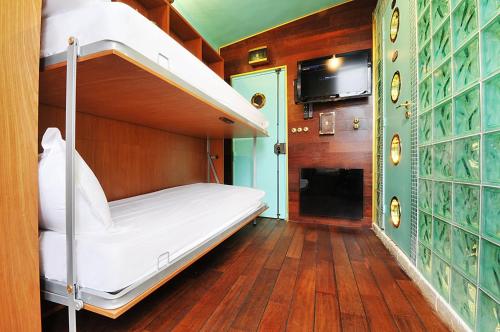 Ce lit superposé se trouve dans un dortoir doté d'une télévision. dans l'établissement Paris Marais Tiny Boat MERRIB, à Paris