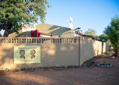 a fence with a sign on it next to a house at Punkinheads Guesthouse in Kasane
