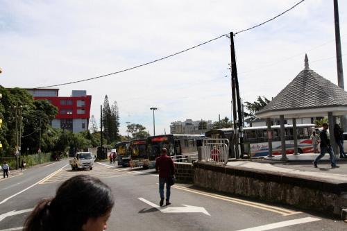 a man crossing a street in a city with buses at Lux Penthouse Apartment 3 bedrooms Quatre Bornes in Quatre Bornes
