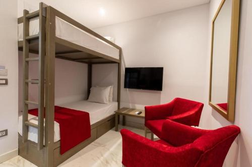 premium sea porto marina suite في العلمين: غرفة نوم مع سرير بطابقين وكرسيين حمر