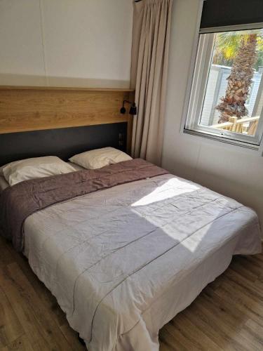 un grand lit dans une chambre avec une fenêtre dans l'établissement Petit coin de paradis à la Yole, à Vendres