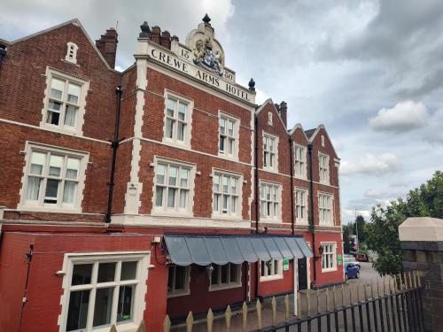 an old red brick building with a clock on it at Crewe Arms Hotel in Crewe