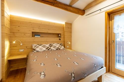 a bedroom with a bed with a wooden wall at Baita La Cascata in Isolaccia