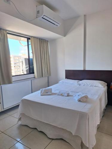 um quarto com uma cama branca com duas toalhas em Studio Ibiza 74 Boa Viagem em Recife