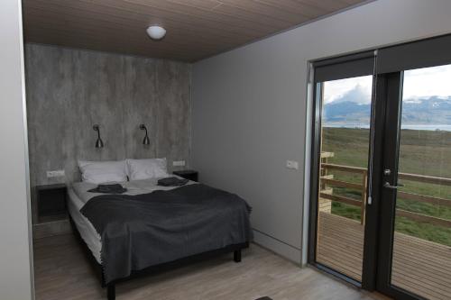 a bedroom with a bed and a large window at Dis Cottages in Grundarfjordur