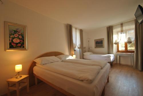a hotel room with two beds and a window at B&B alla Pieve in Calceranica al Lago