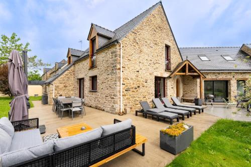 a patio with couches and chairs in front of a building at Gite Ti Coz piscine intérieure in Caden