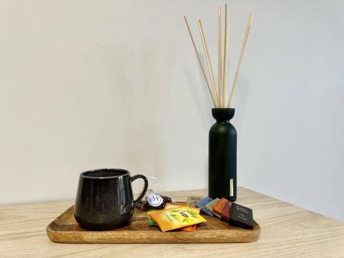 a black coffee mug on a wooden tray with a vase at Le Poète - Appartement Confort - Parking Privé - WIFI in Gradignan