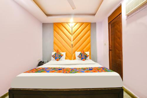Schlafzimmer mit einem großen Bett mit einem Kopfteil aus Holz in der Unterkunft FabHotel Iris Lite in Neu-Delhi