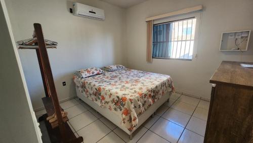 een kleine slaapkamer met een bed en een raam bij Casa 1km praia in São Mateus