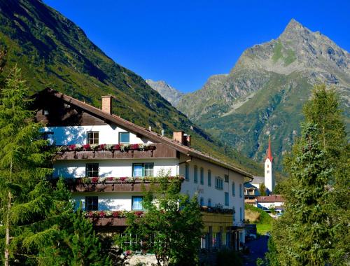 ガルチュールにあるClubdorf Hotel Alpenroseの山の前のバルコニーに花が咲く建物