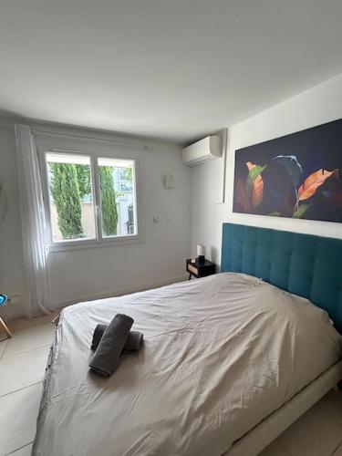 - une chambre blanche avec un grand lit et une tête de lit bleue dans l'établissement L'Alyscamps Appartement Arles, à Arles