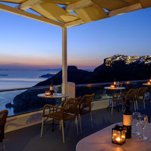 a restaurant with a view of the ocean at night at Vallas Apartments & Villas in Firostefani