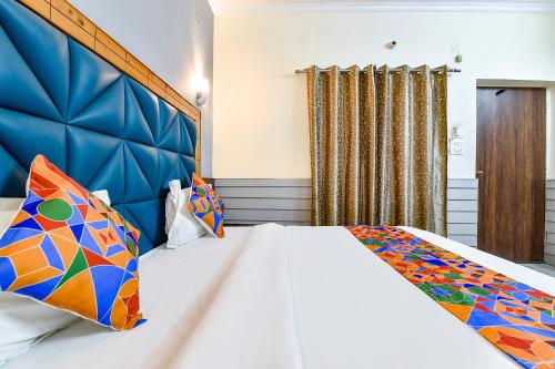 1 dormitorio con 1 cama grande y cabecero azul en FabHotel KK Residency, en Mājra