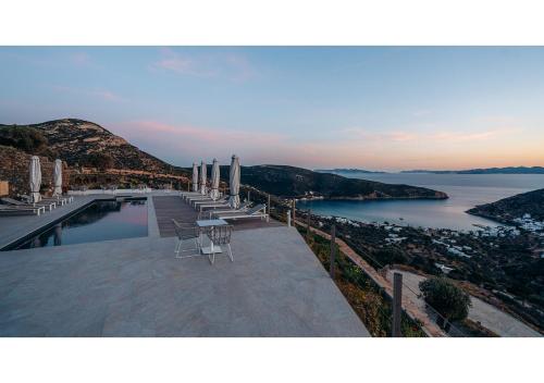 a swimming pool with chairs and a view of the water at Melianthos Villas in Vathi, Sifnos