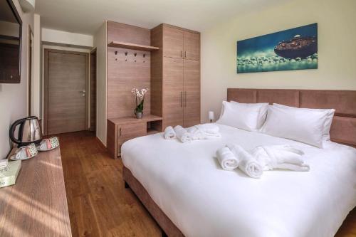 a bedroom with a large white bed with towels on it at Vitta Hotel Superior in Budapest