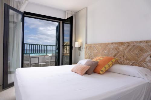 ein Schlafzimmer mit einem großen weißen Bett und einem Balkon in der Unterkunft Hoposa Niu in Cala de Sant Vicent